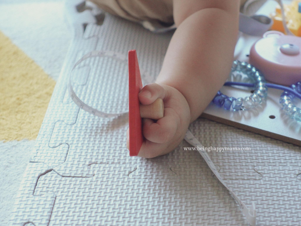 Baby is developing her pincer grasp by holding a puzzle piece.