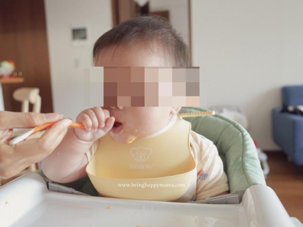 Baby feeding herself using the weaning spoon.