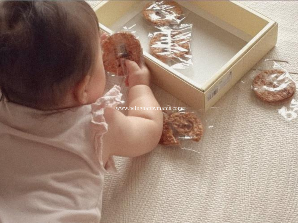 Baby picking up individually wrapped snacks to practice pincer grasp.